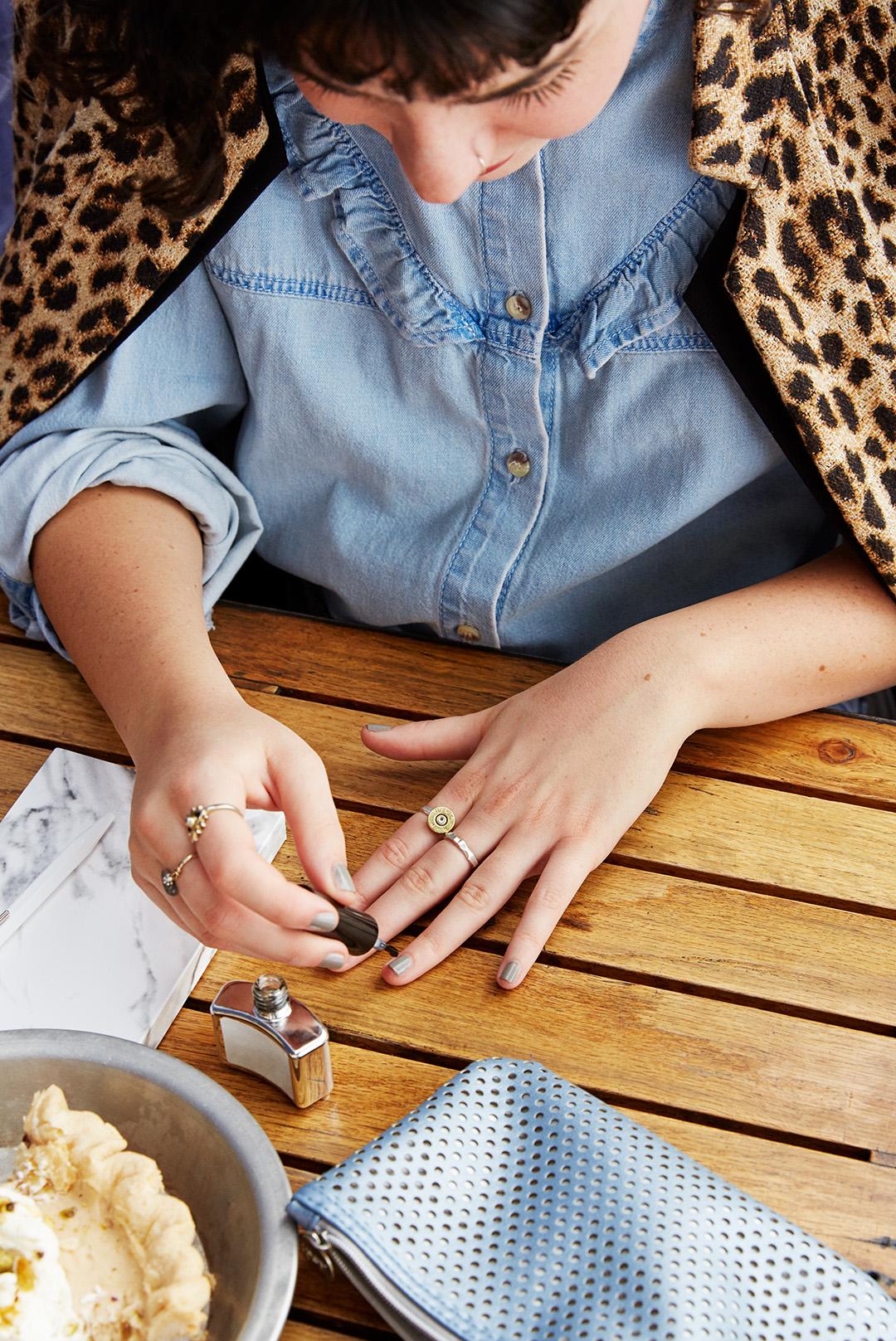 A photo of a woman applying a nail polish on a wooden table Desktop