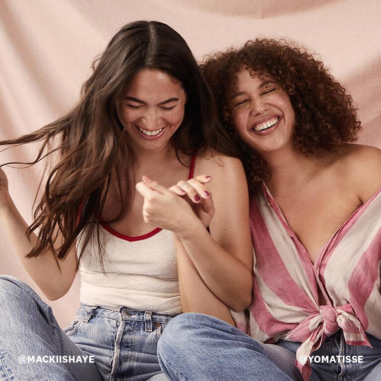 An image of models with wavy and curly hair holding hands while smiling big Desktop