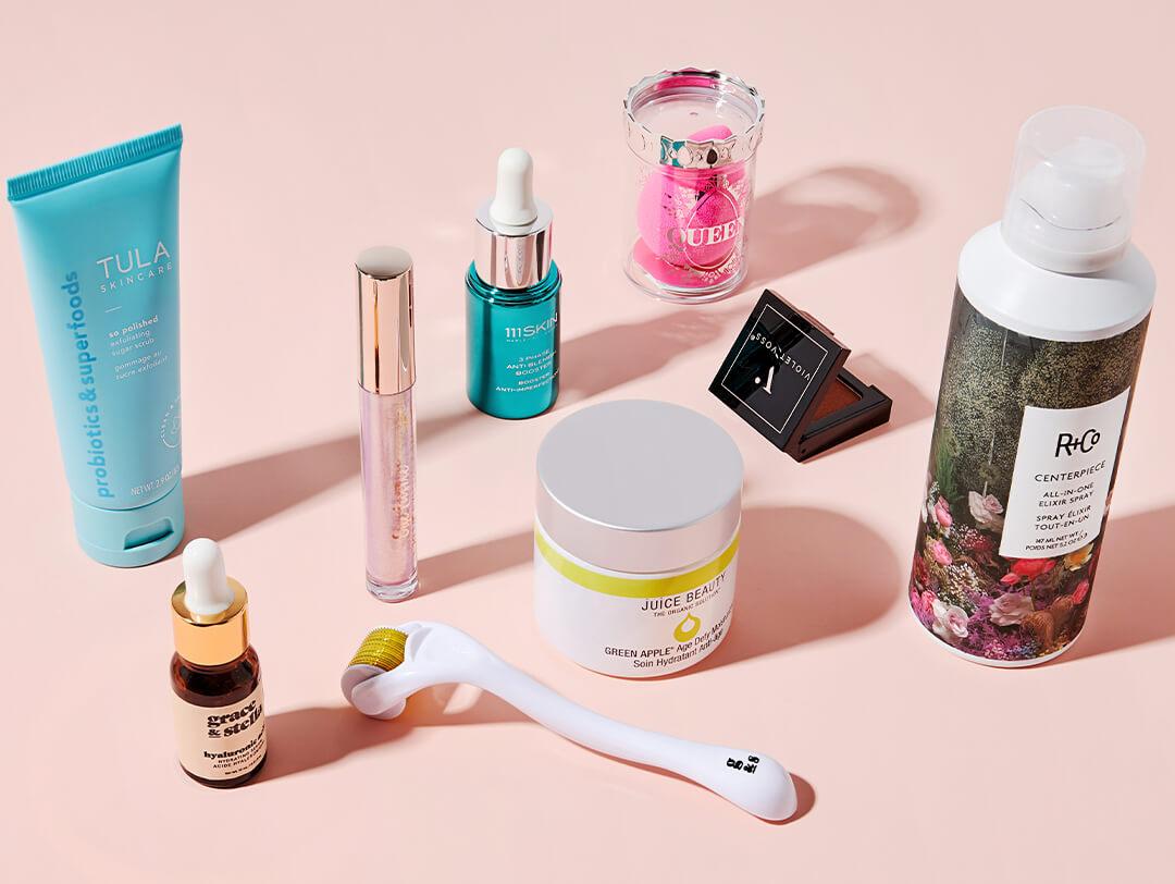 Flat lay image of hair care, makeup, and skincare products and tools on pink background Desktop