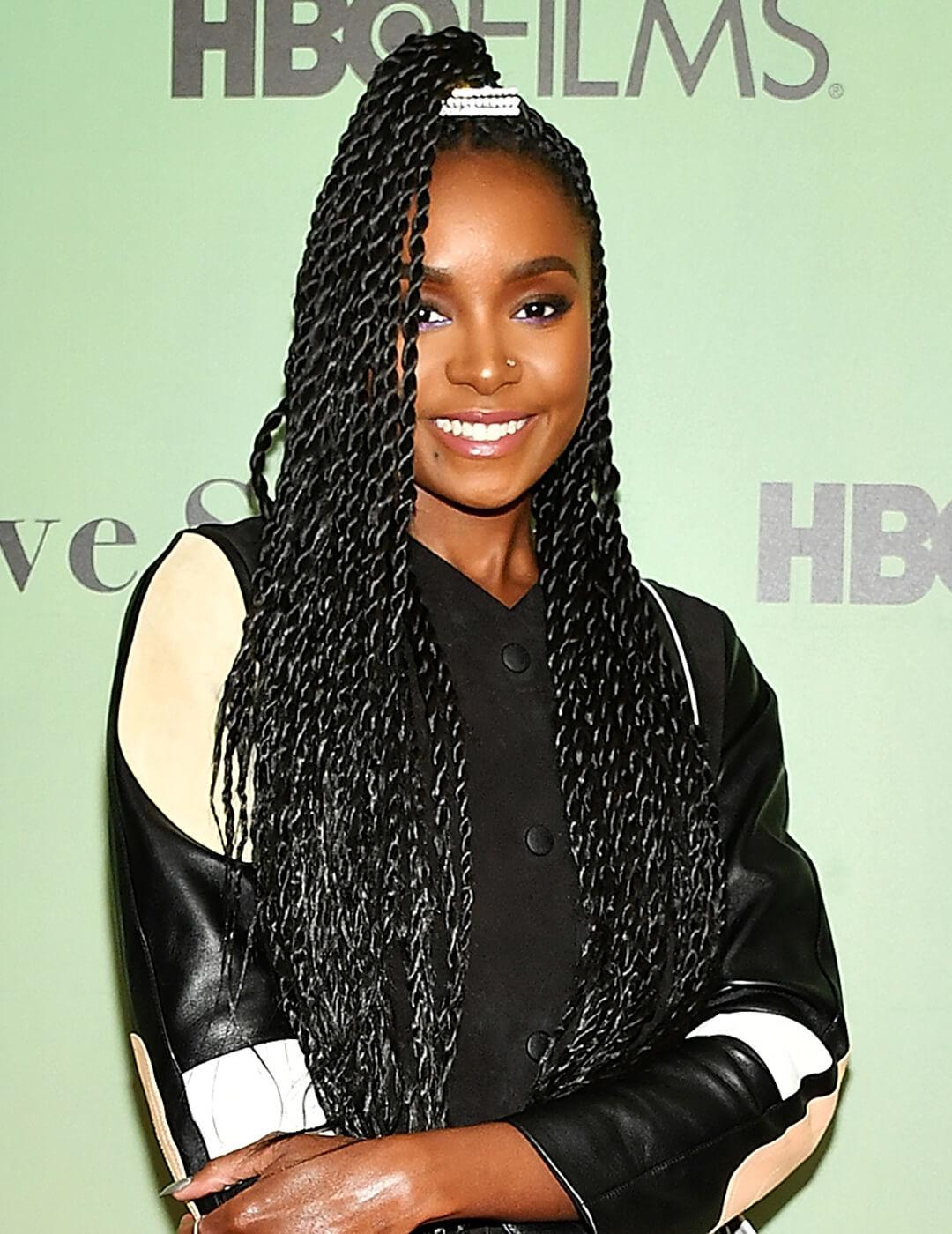 Kiki Layne rocking a high ponytail twists hairstyle, cream, white, and black leather jacket, and smoky eyeshadow makeup look paired with nude lips Desktop