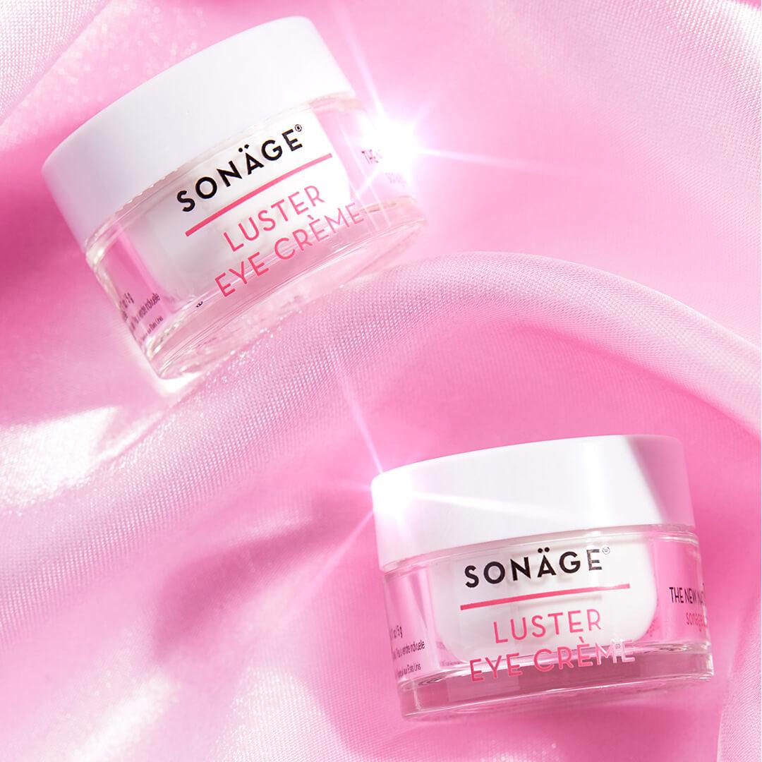 Image of two jars of SONÄGE SKINCARE Luster Eye Crème on pink silk cloth Mobile