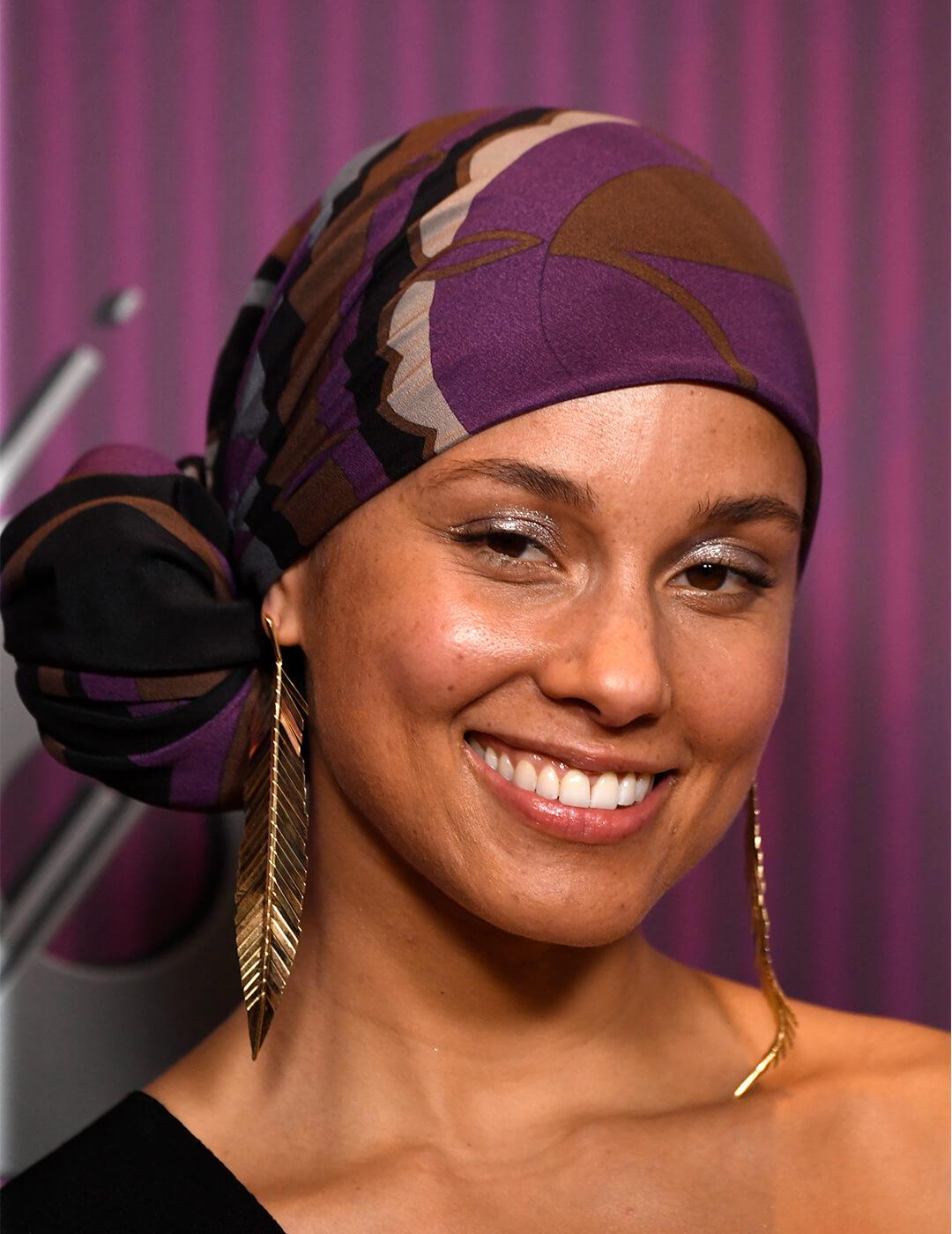 Close-up of a smiling Alicia Keys rocking a headwrap and danging, gold feather earrings Desktop
