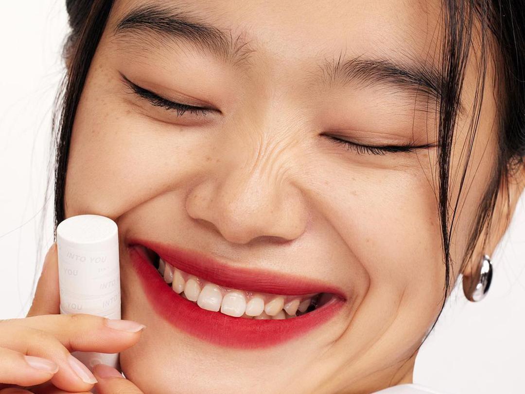 A closeup of a model holding a lipstick with bold red lip color Desktop