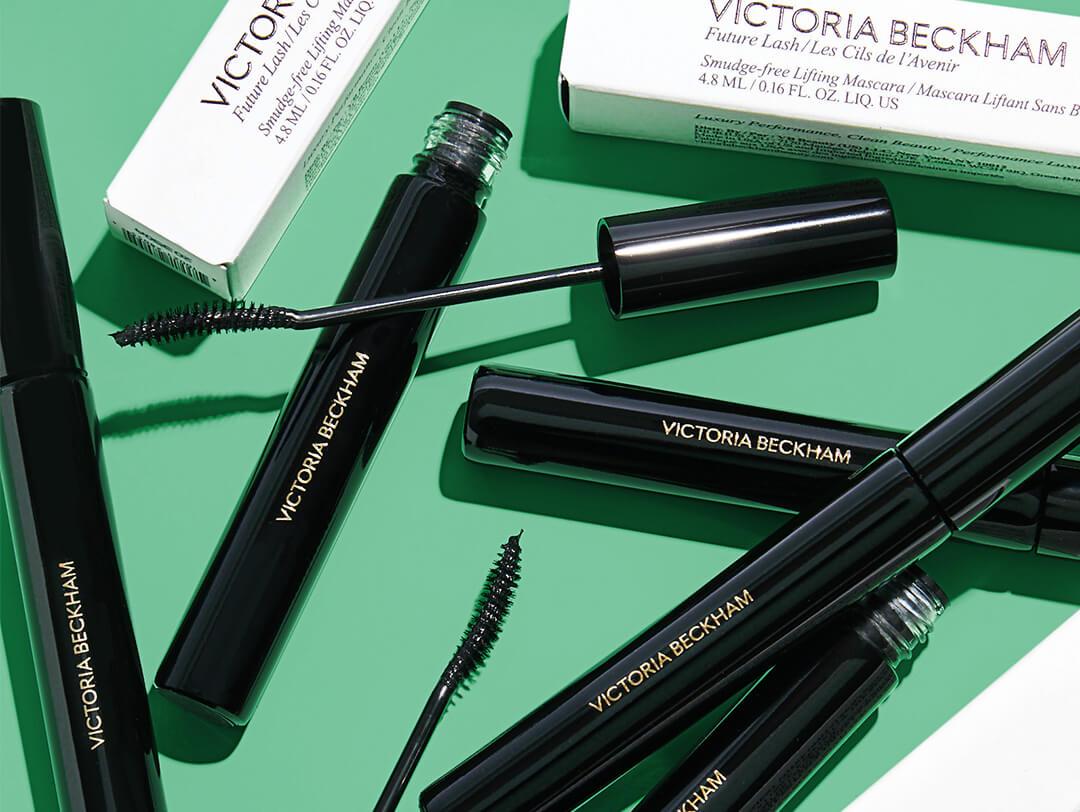 Tubes of VICTORIA BECKHAM BEAUTY Future Lash, Smudge-Free Lifting Mascara scattered on green background Desktop