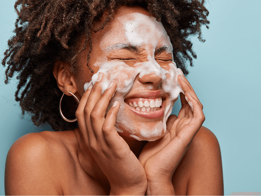 Close-up of a woman of color washing her face with foam cleanser Desktop