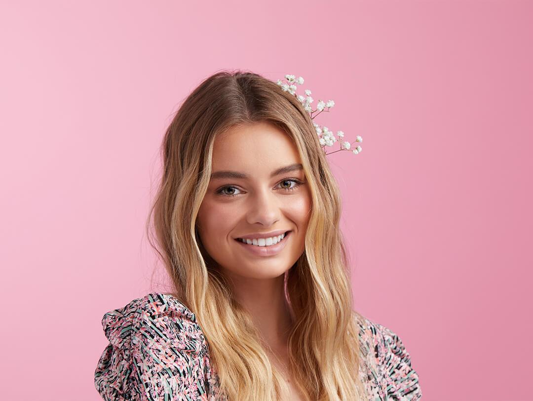 An image of a model with ombre hair adorned with white flowers wearing a floral outfit Desktop