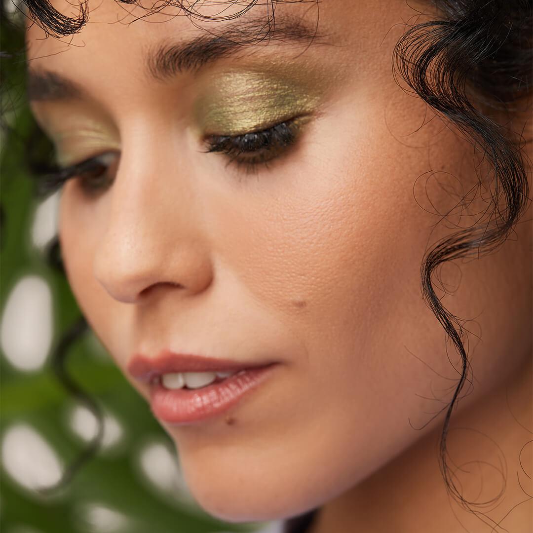 Close-up of a model with a shimmery emerald green eyeshadow makeup look looking down Mobile