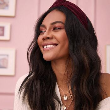 An image of a model with black wavy hair wearing a dark maroon headband Mobile