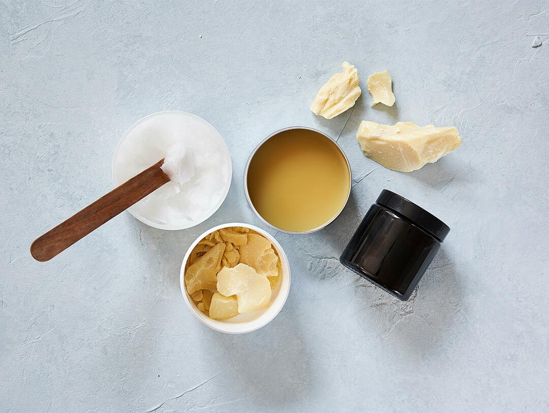 Top view image of different types of waxes in containers and jars on turquoise background Desktop