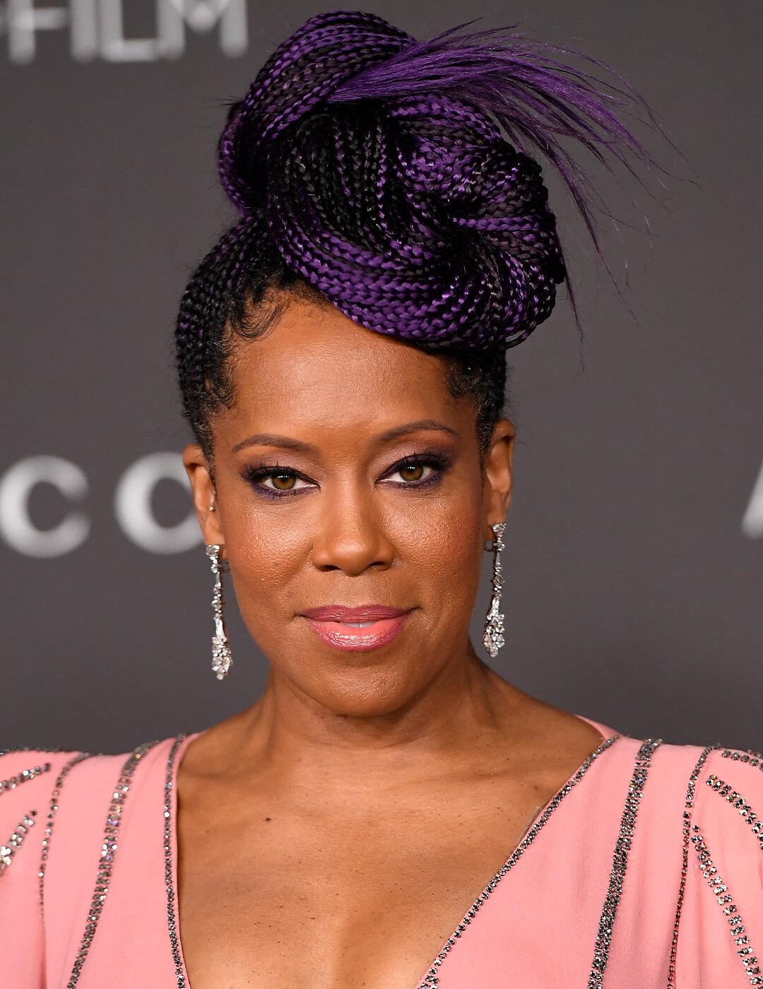 Regina King rocking a purple braided updo hairstyle, smoky eyeshadow makeup, silver dangling earrings, and pink and silver sequins dress Desktop