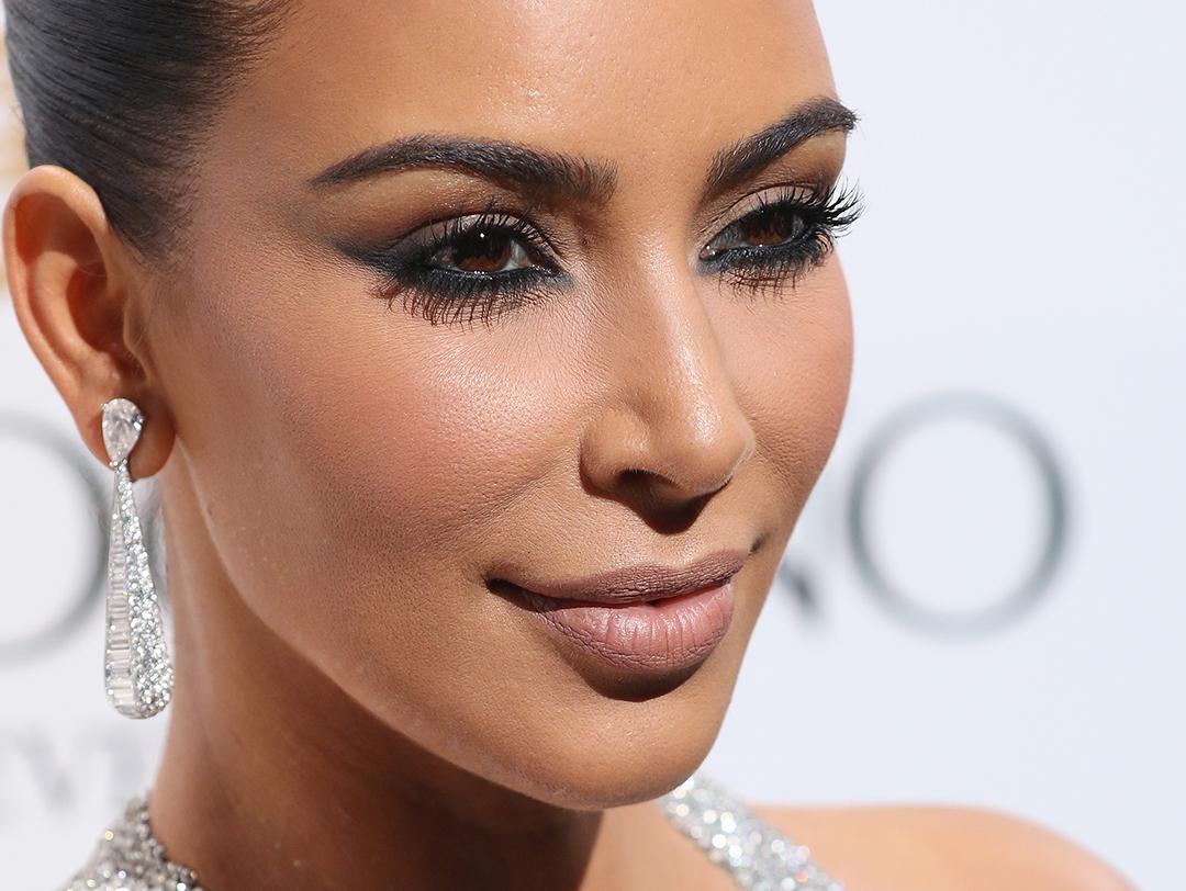 A photo of Kim Kardashian wearing a diamond waterdrop earrings, nude lipstick, and a black eyeliner Desktop