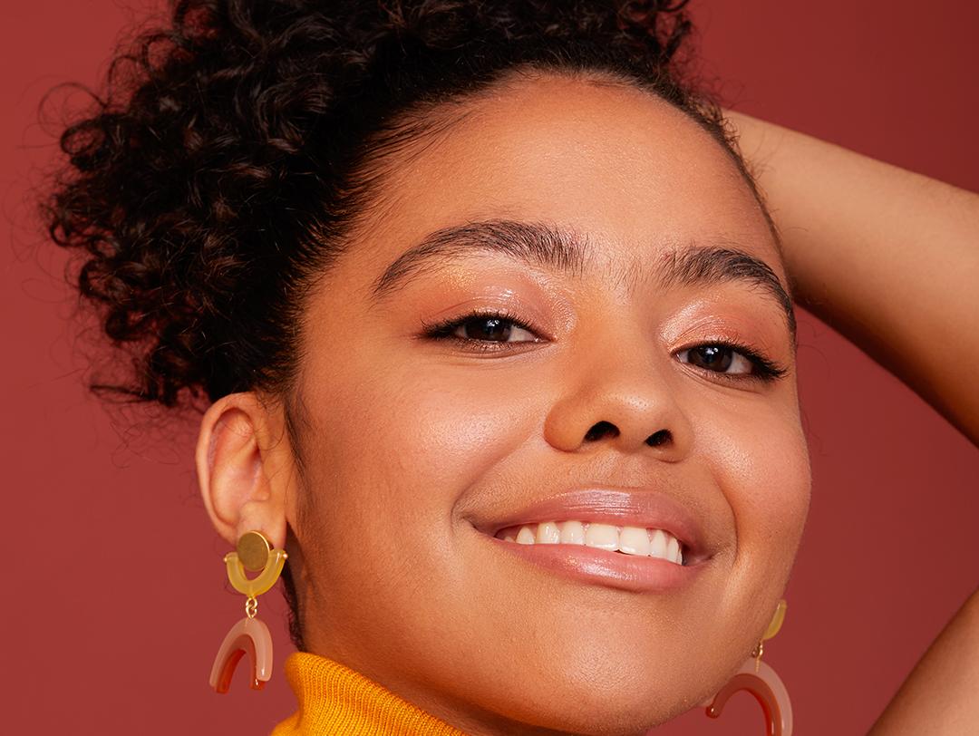 A photo of a woman with a nude look wearing an orange turtleneck and arched style earrings Desktop