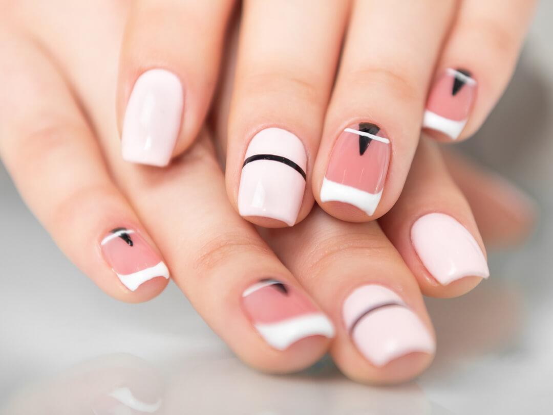 Close-up image of a woman's hands with pink, black, and white graphic nail art Desktop