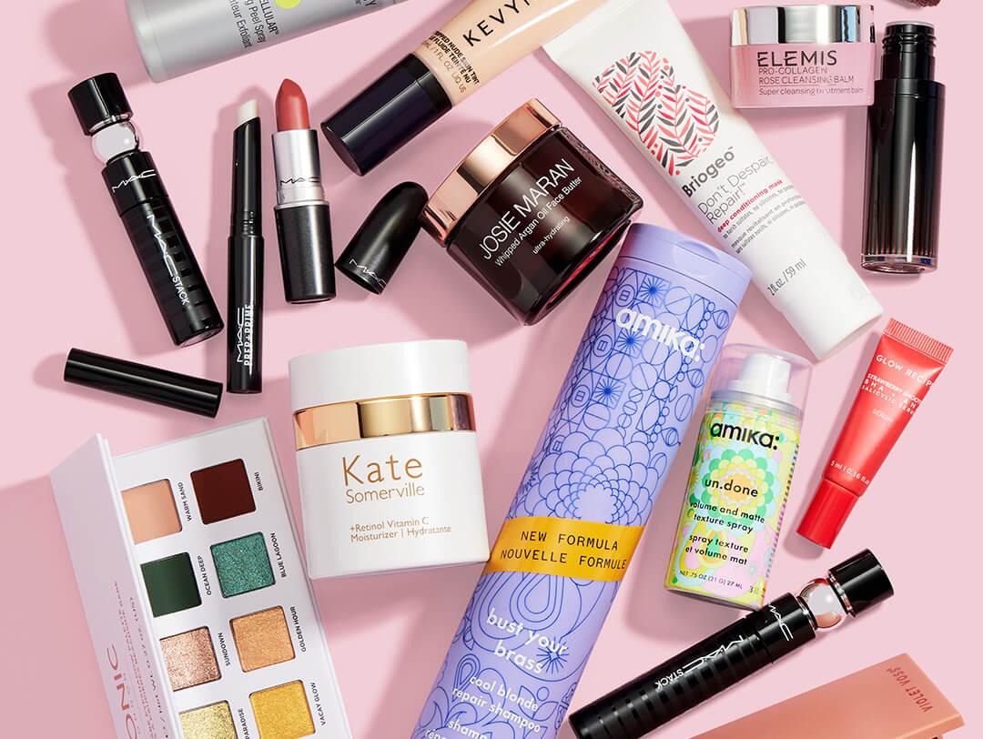 Beauty and makeup products from various brands scattered on pink background Desktop