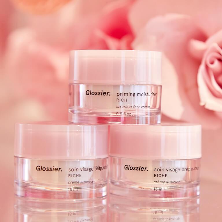 An image of three GLOSSIER Priming Moisturizer Rich stacked with roses as backdrop Desktop