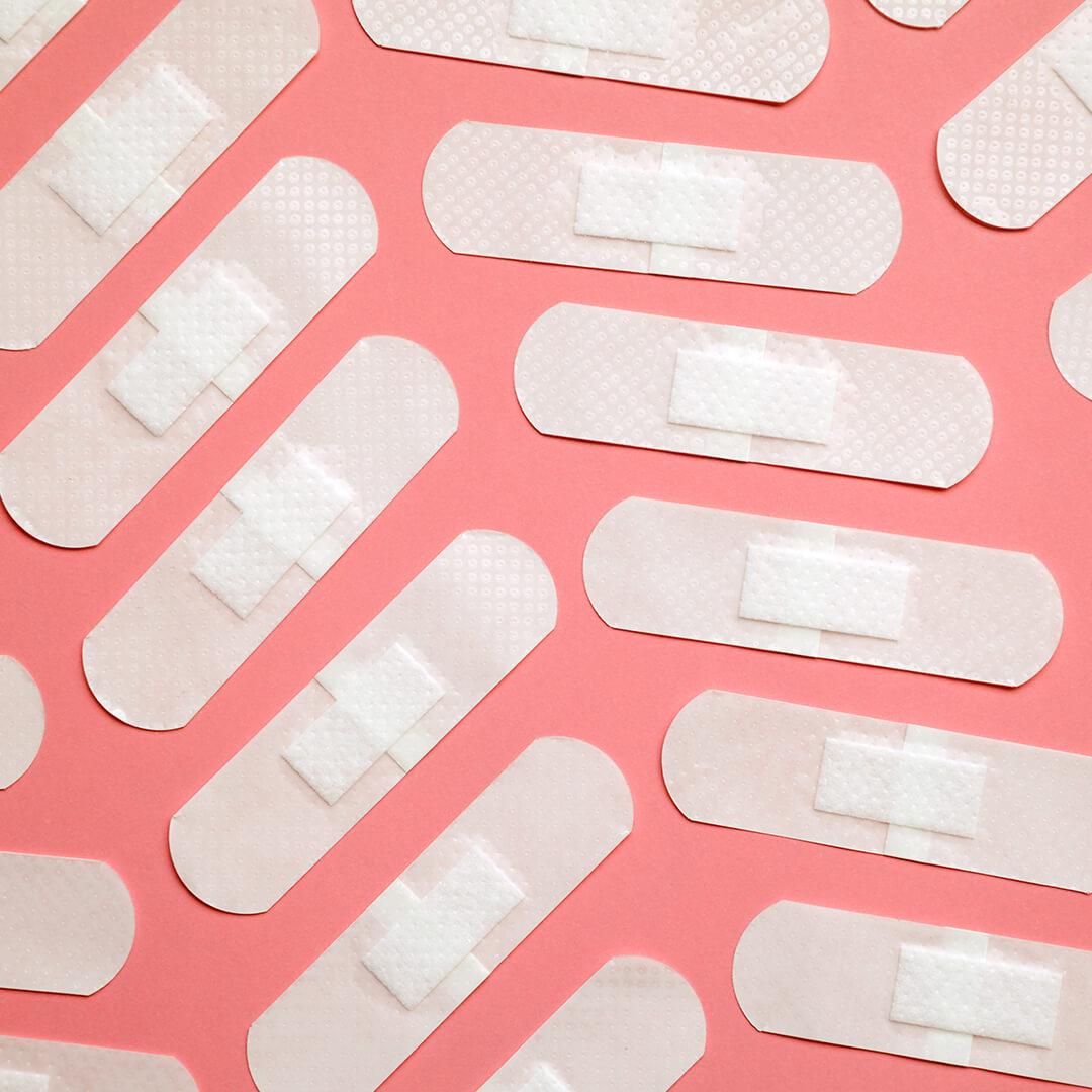 Many white adhesive band aids arranged on pink background Mobile