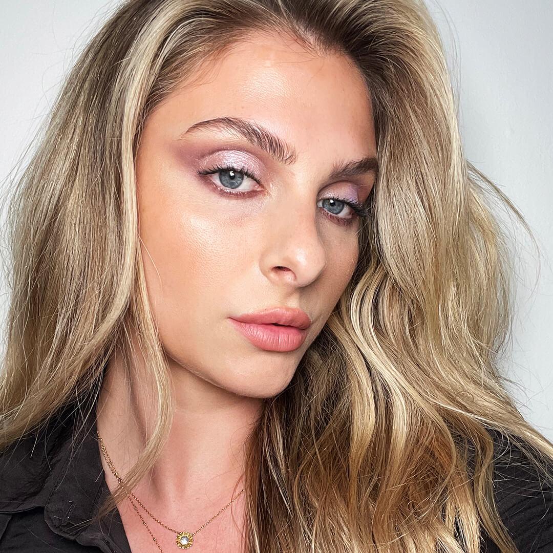 Close-up of a woman rocking a shimmery lavender eye makeup look paired with nude lips Mobile