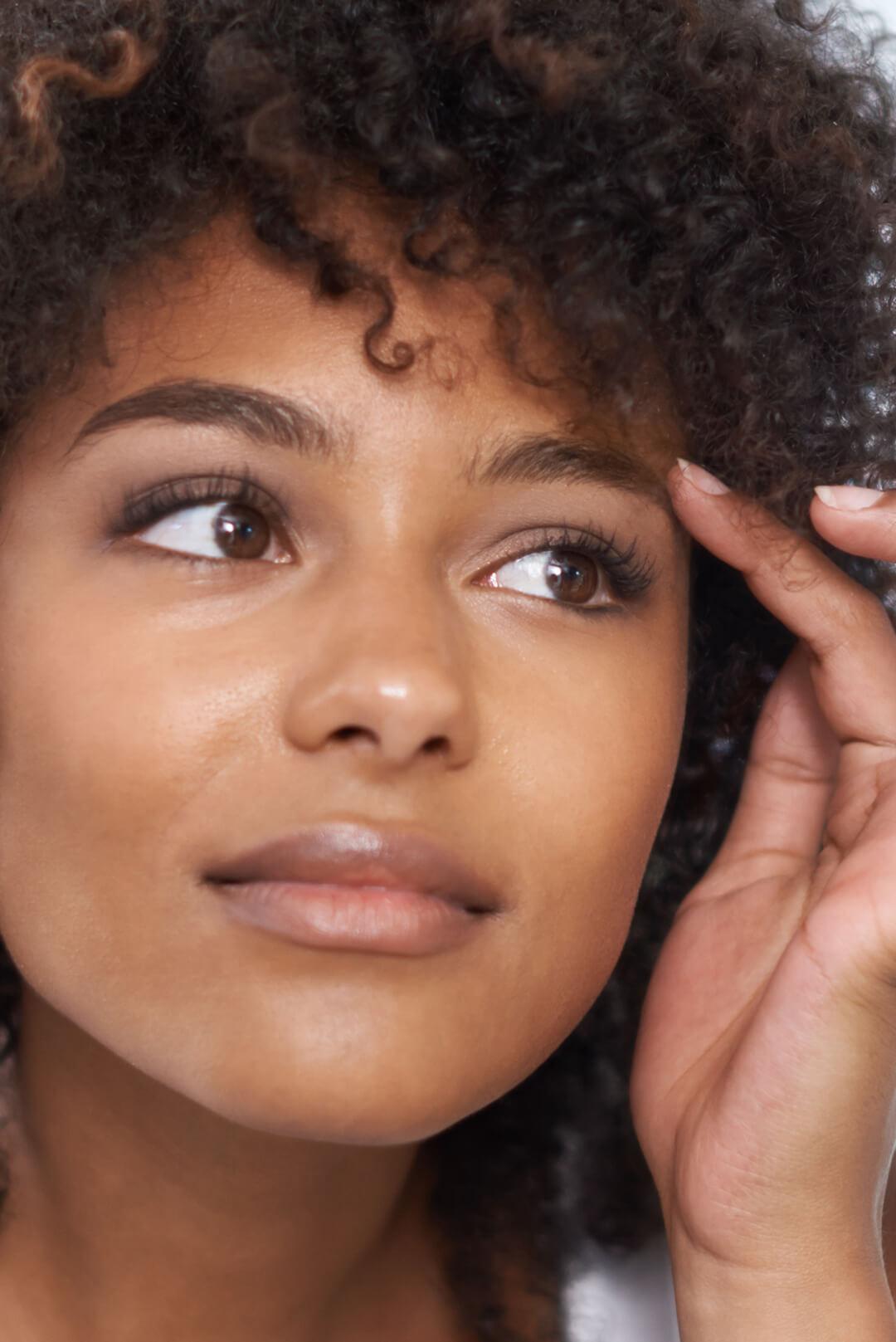 Close-up of a beautiful woman with curly hair touching her eyebrow Desktop