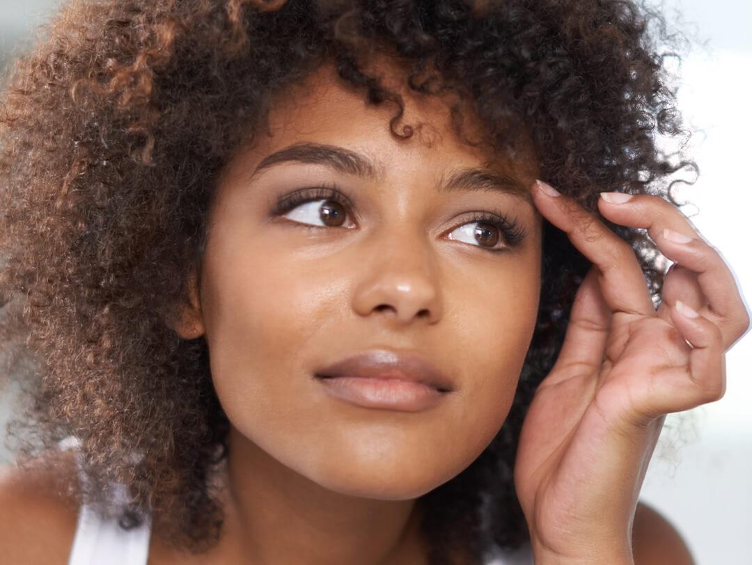 Close-up image of a woman of color touching her eyebrow Desktop