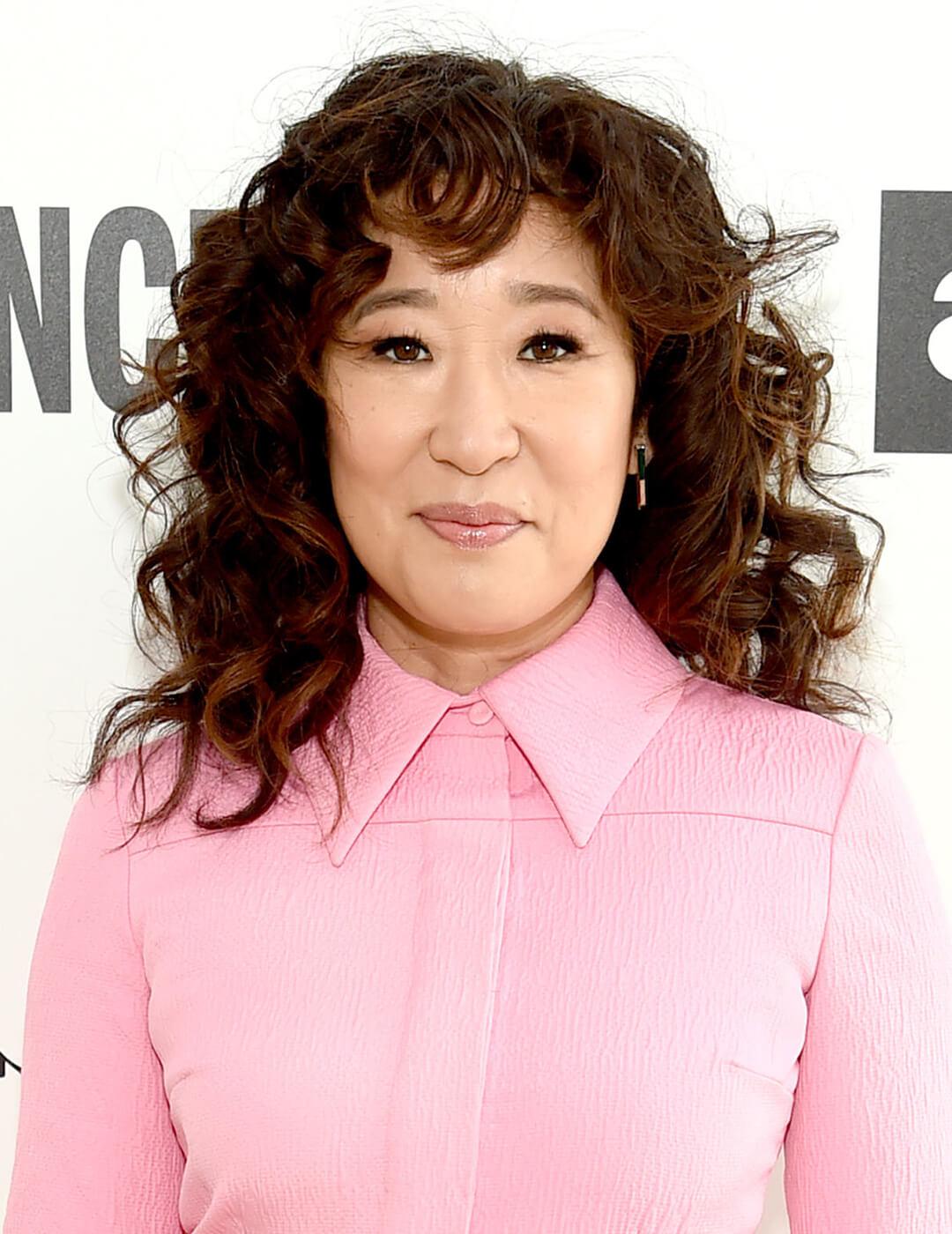 Smirking Sandra Oh rocking a wavy hairstyle and pink jumpsuit Desktop