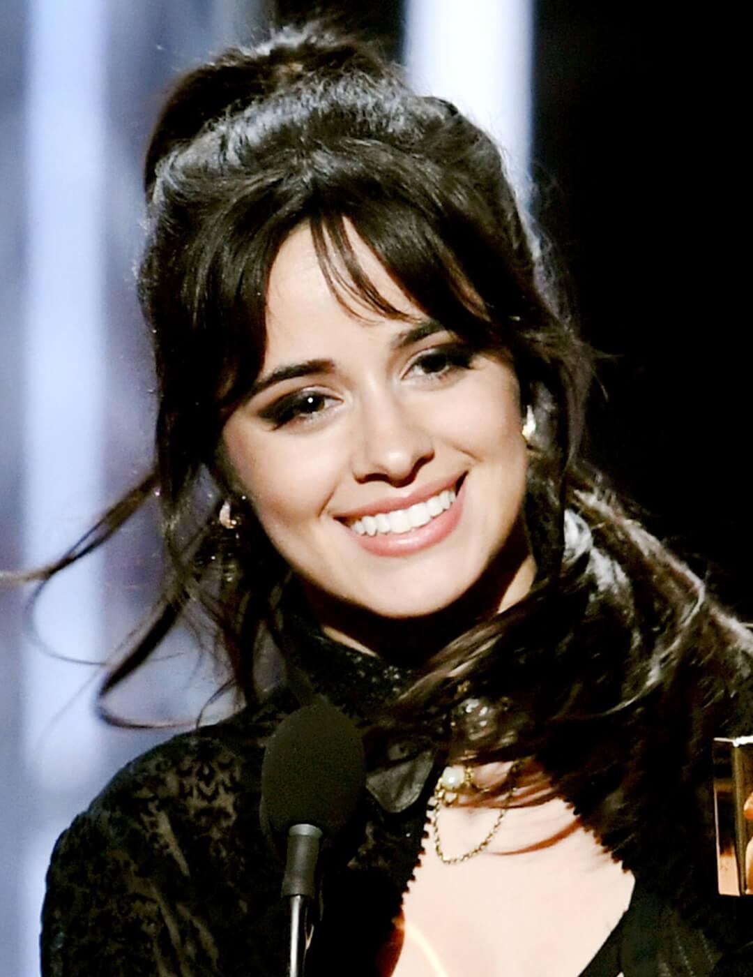 Camila Cabello smiling in an all-black ensemble and dark smoky eye makeup look Desktop