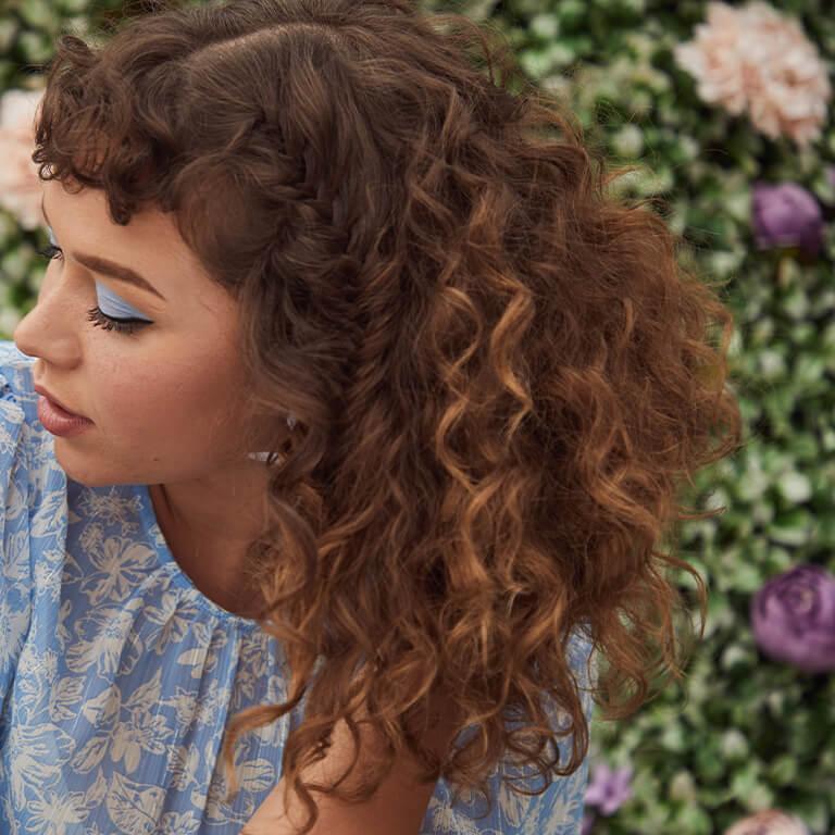 A close-up image of a curly-haired model with partly hidden braids Desktop