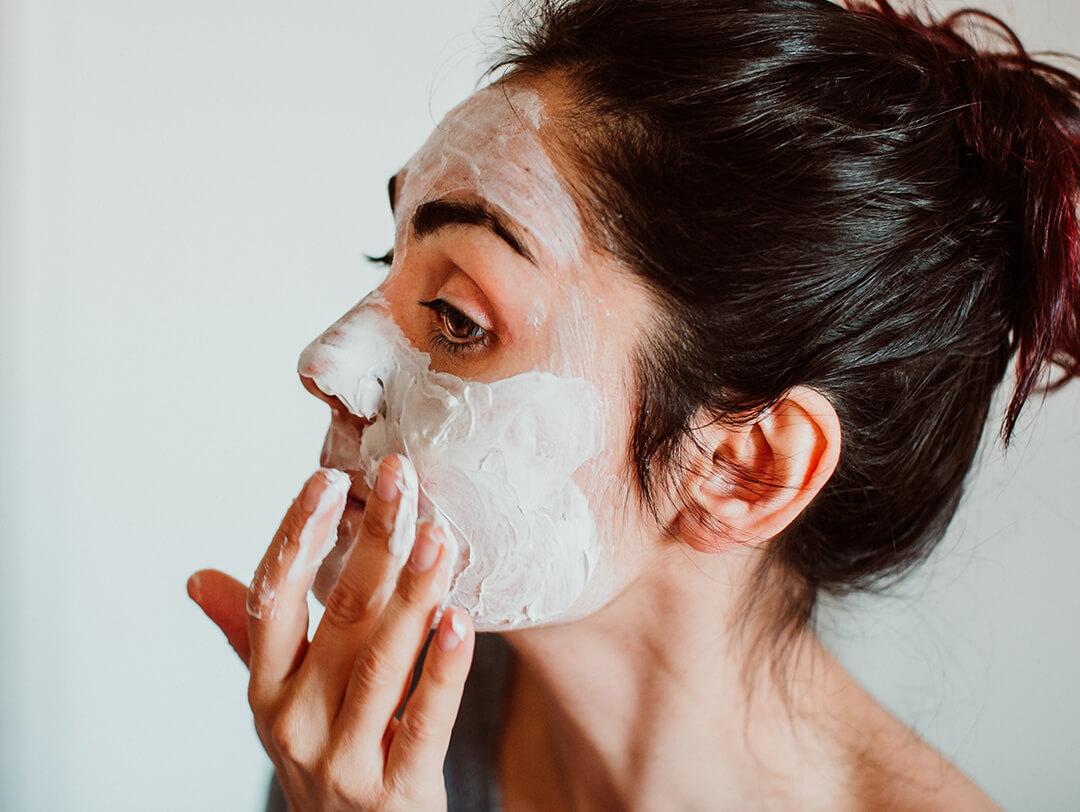 Close-up of a woman putting mud mask on her face Desktop