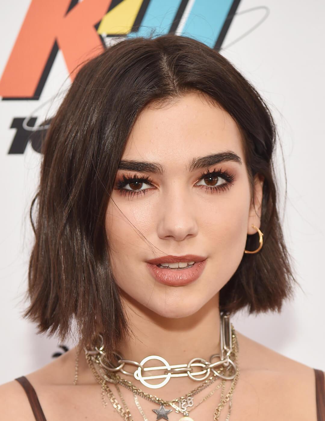 An image of Dua Lipa looking fierce and fresh in her brown semi-smokey eyeliner and lipstick along with chained necklace Desktop