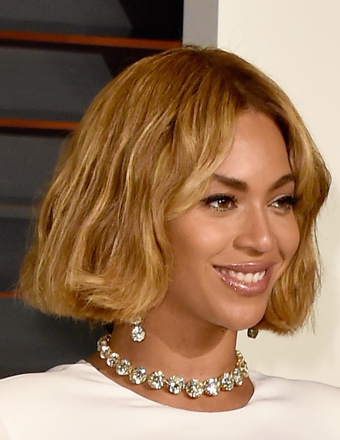 An image of Beyonce beautifully smiling with her glossy, nude lipstick accentuated with a white-gold necklace and earring Desktop