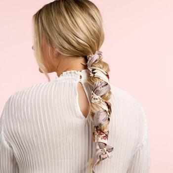 An image of a blonde model showing her braids interlaced with a white and lilac floral scarf Mobile