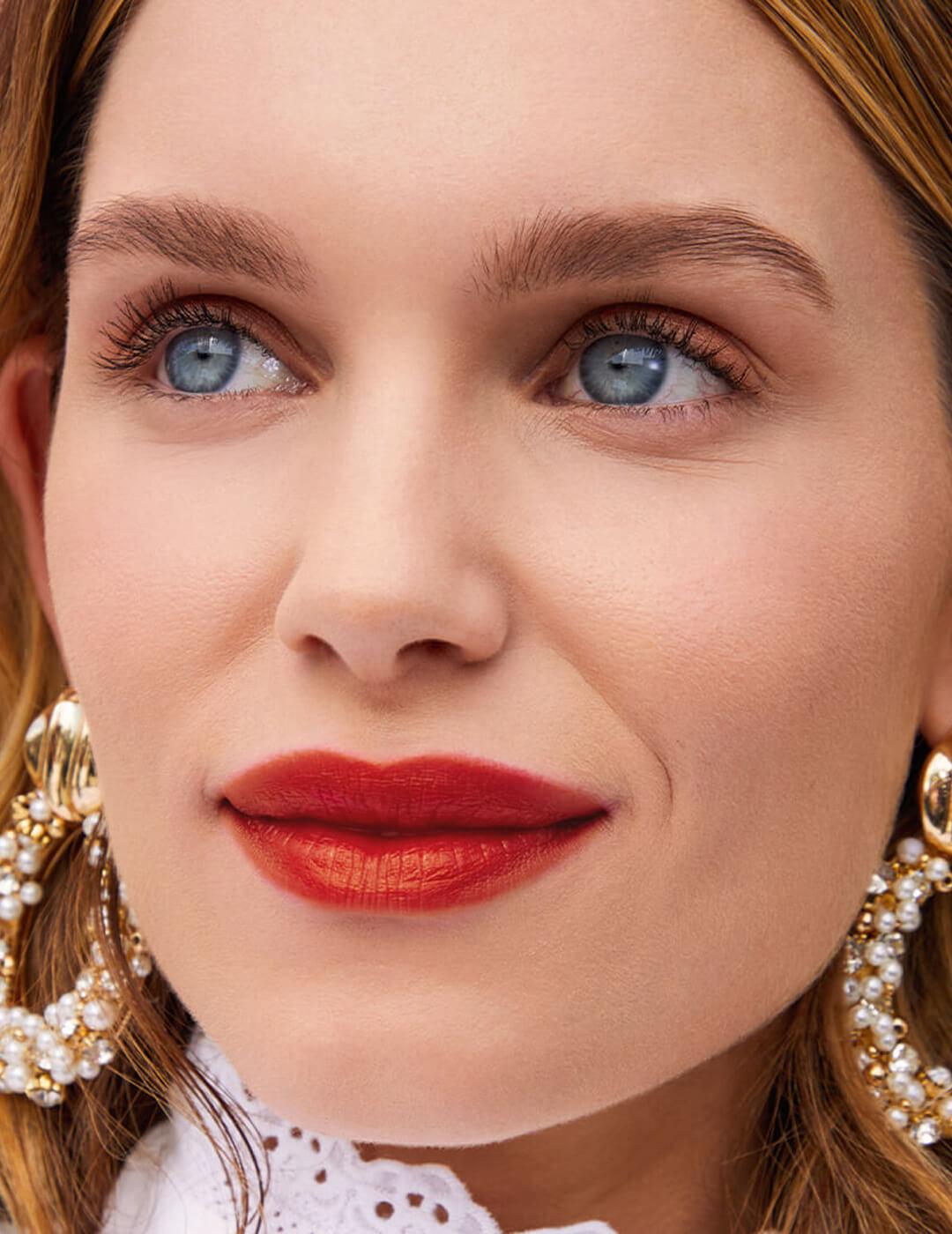 An image of a model wearing burnt red lipstick and nude eyeshadow. Desktop