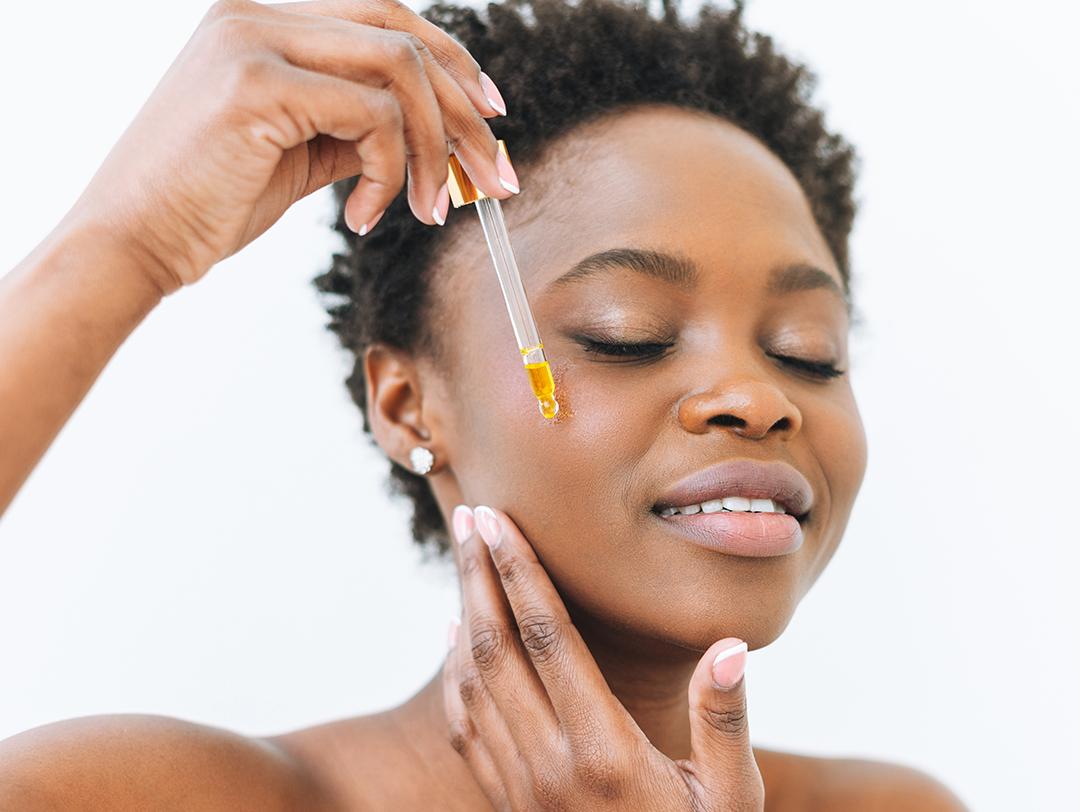 A photo of a woman applying facial oil on her cheek Desktop