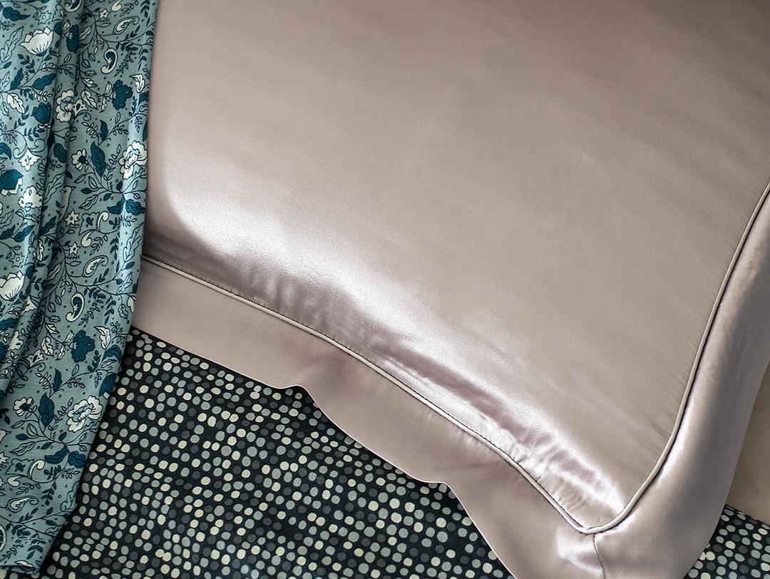 A photo of a pillow with a silk pillowcase and blue green sheets Desktop