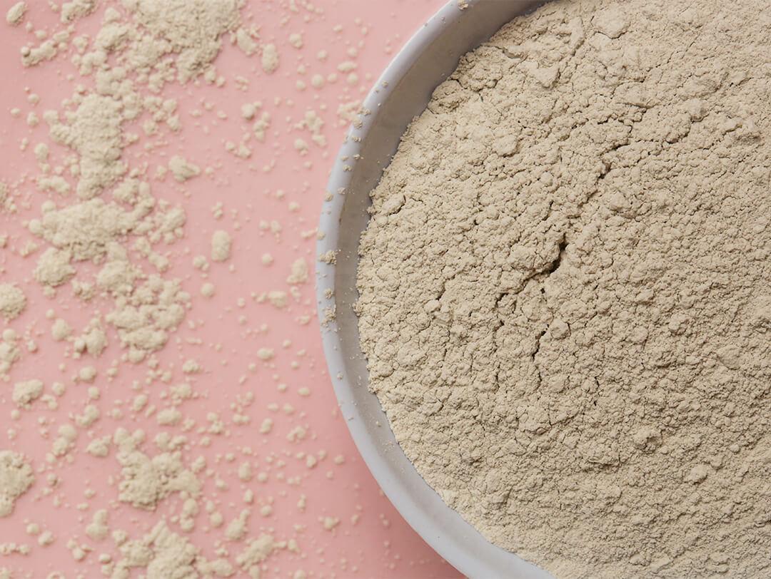 Image of a bowl of kaolin clay powder on pink background Desktop