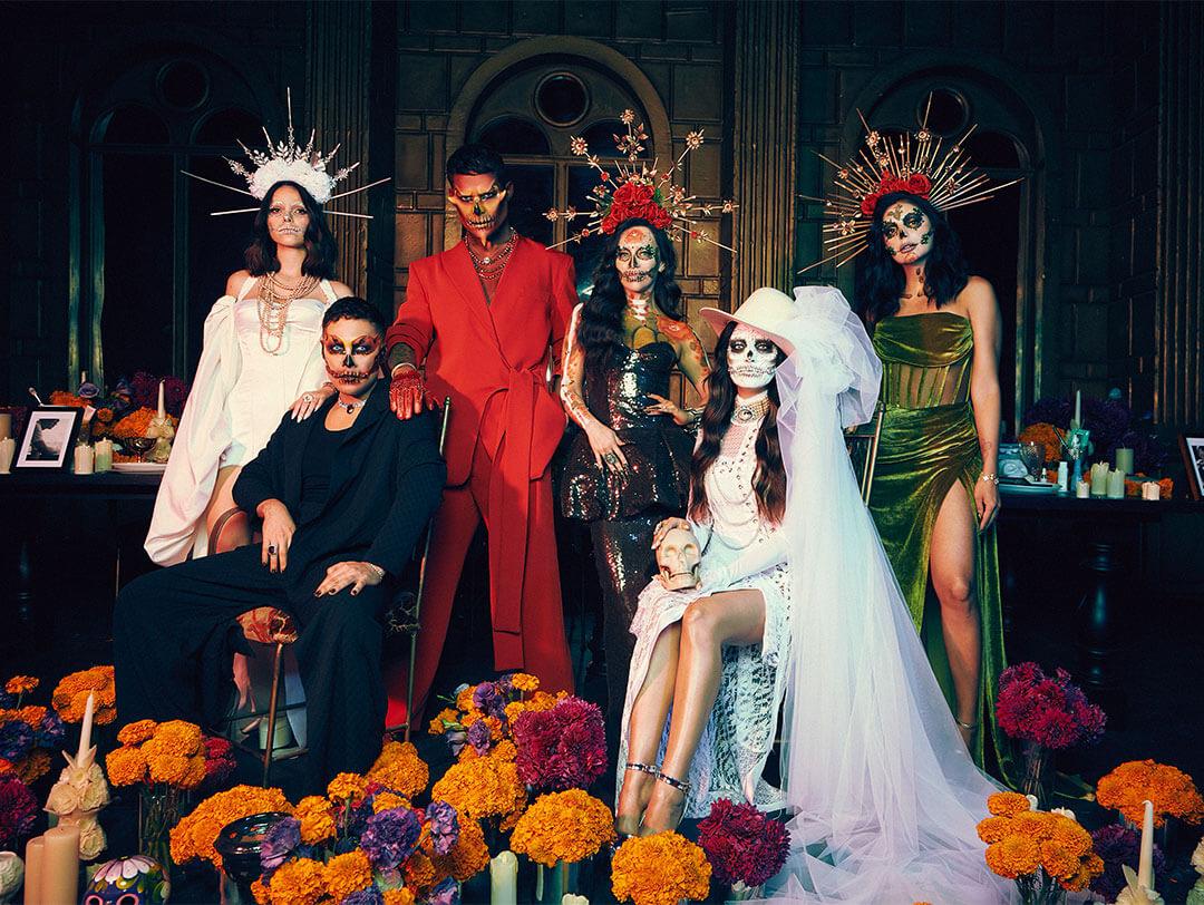 Group of six models in dia de los muertos makeup looks posing among flowers Desktop