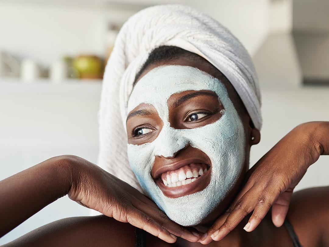 An image of a smiling woman with a mud mask on her face Desktop