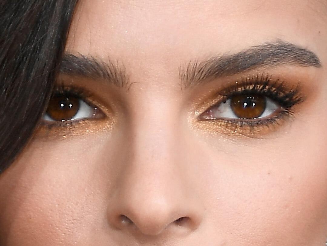 Close-up image of Emily Ratajkowski wearing a dark, shimmery yellow smoky eye makeup Desktop