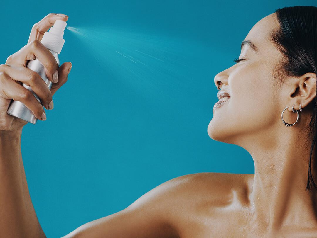 An image of a woman in a sideview spraying mist on her face Desktop