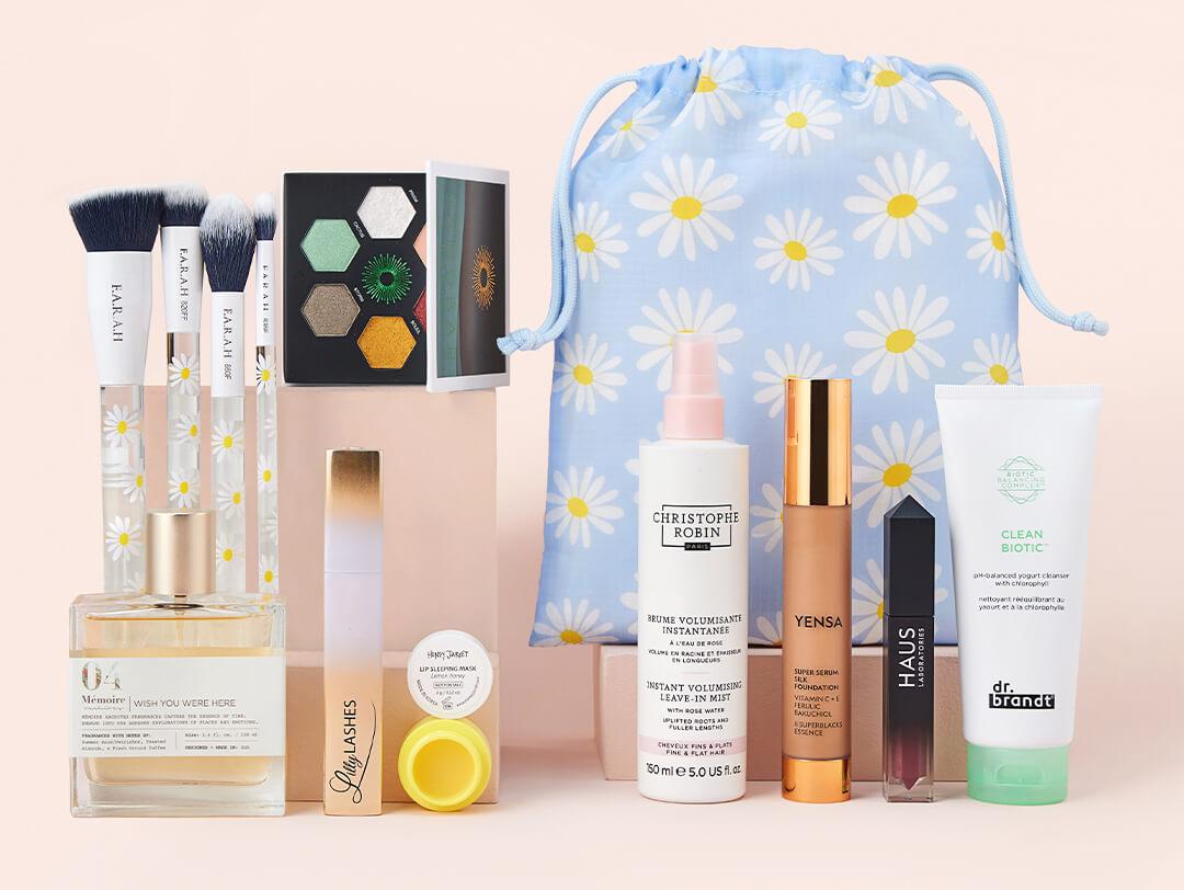 April 2022 Glam Bag Plus bag and beauty products from various brands neatly arranged on light peach background Desktop