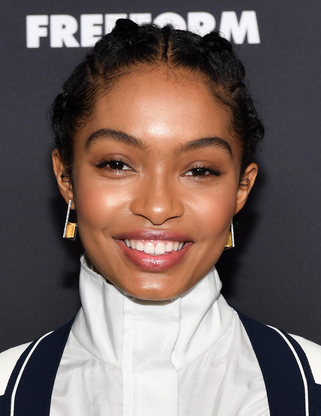 Smiling Yara Shahidi rocking a braided updo hairstyle and no-makeup makeup look Desktop