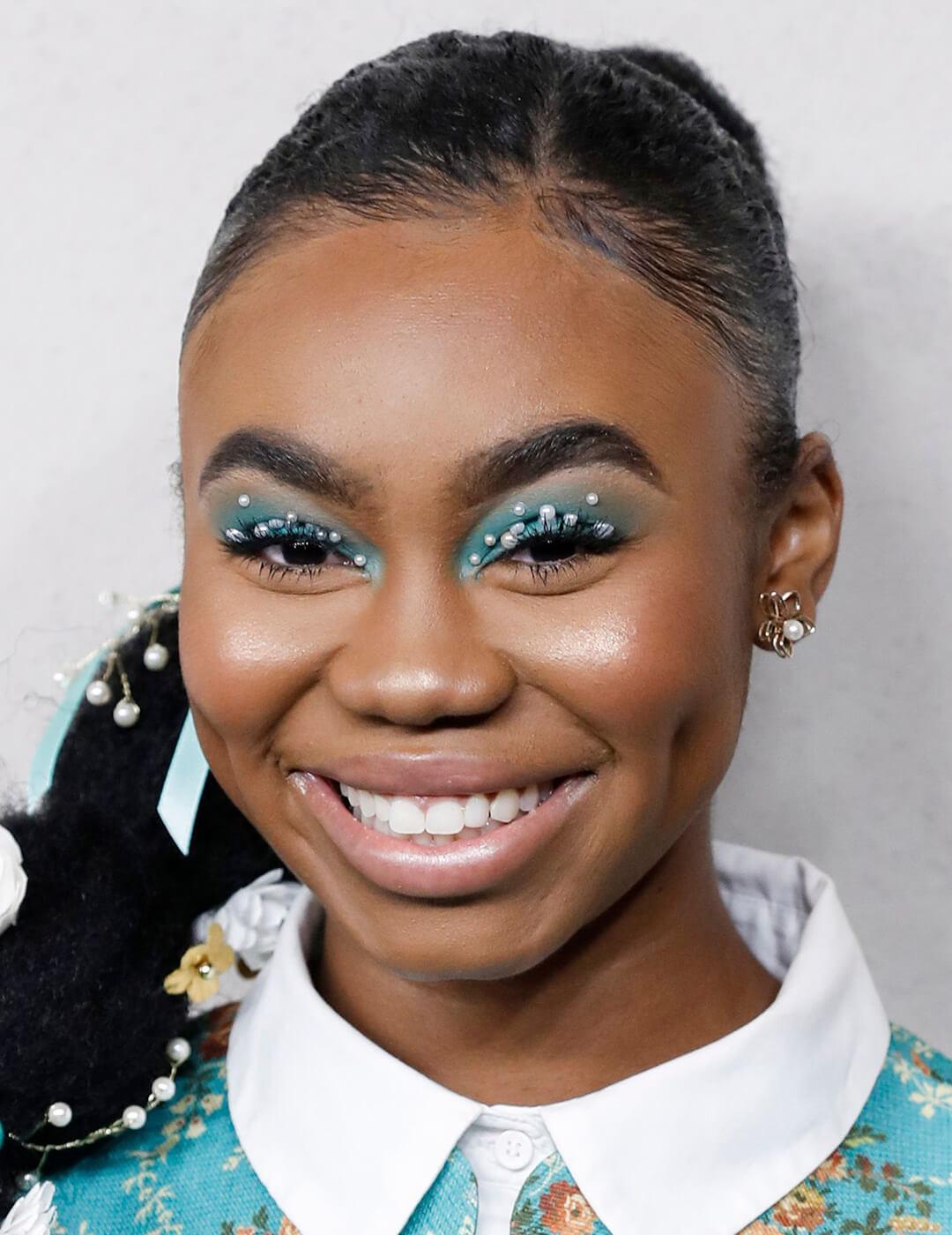 Close-up of a smiling Jordan Rice rocking blue eyeshadow makeup embellished with pearls Mobile