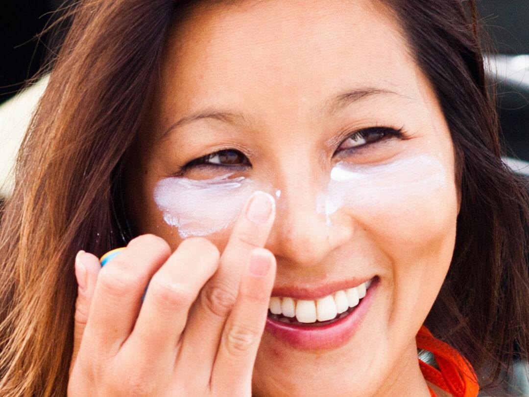 Image of a woman putting white cream under her eyes Desktop