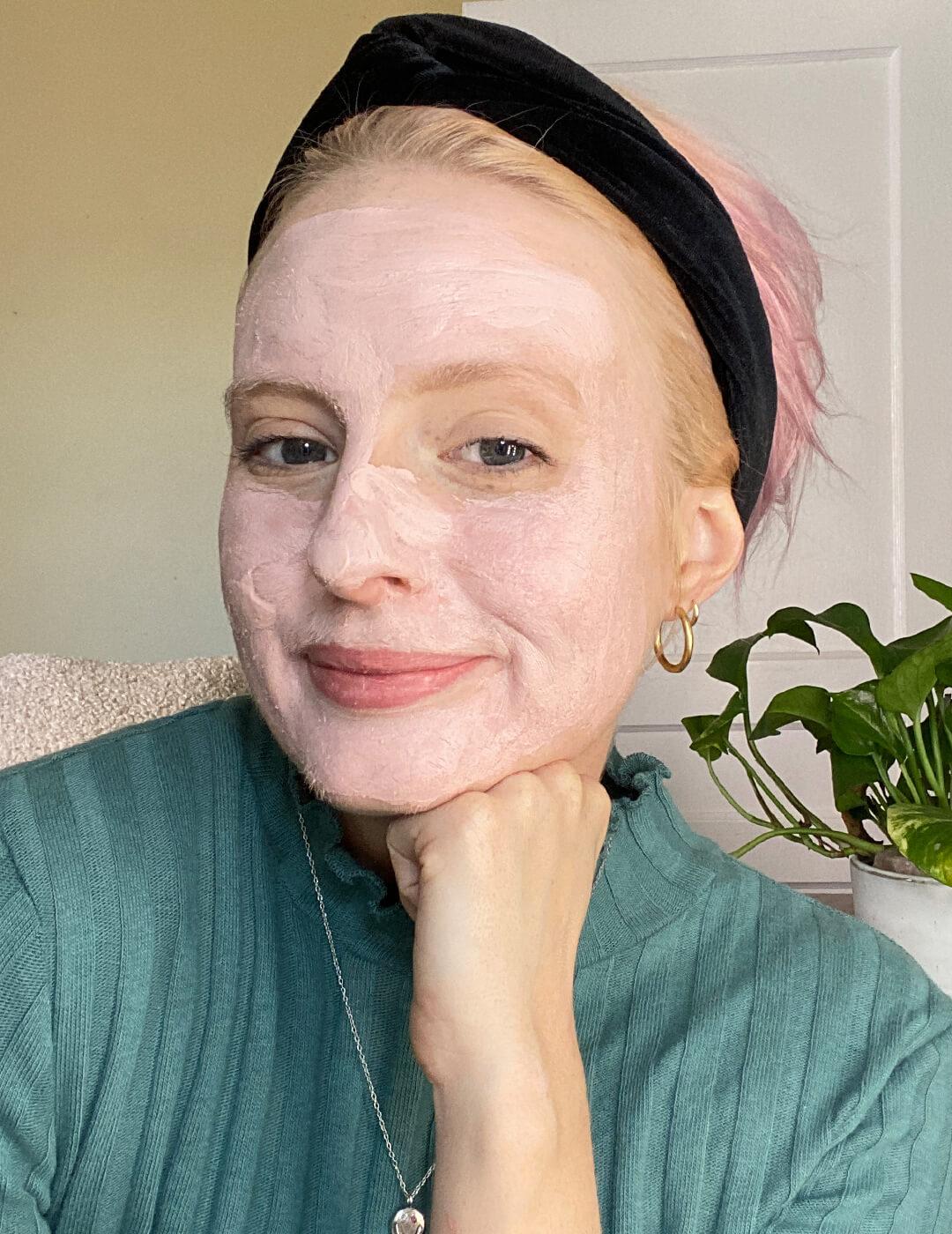 Hannah Cassidy in a green sweater and black headband posing with pink mud mask on her face Desktop