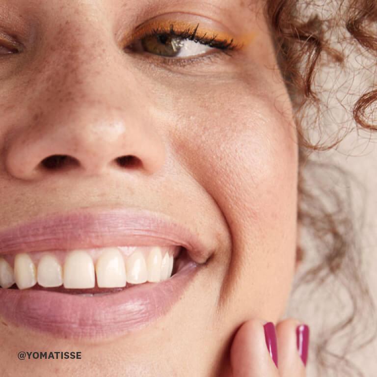 A model smiles after putting on sunscreen. Desktop