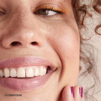A model smiles after putting on sunscreen. Mobile
