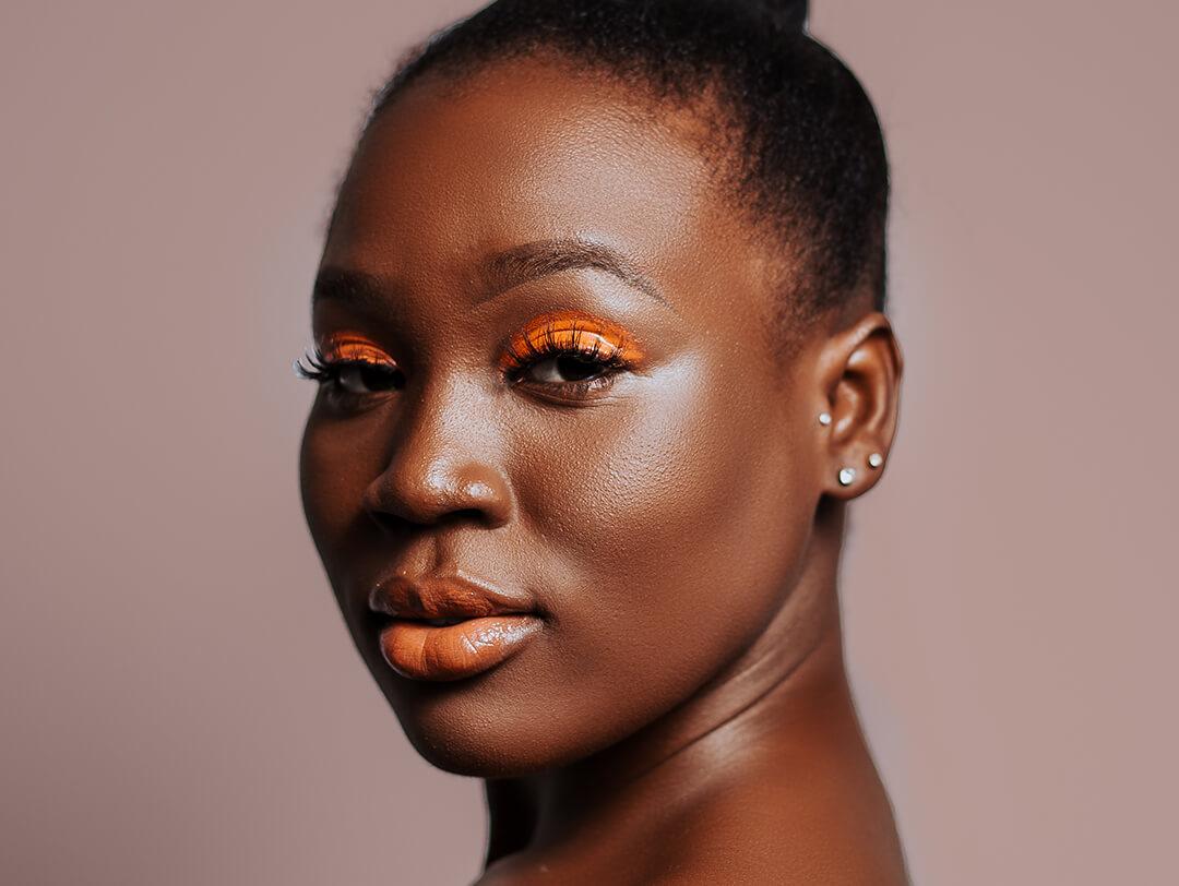 Beauty portrait of a Black woman rocking an orange eyeshadow makeup look Desktop
