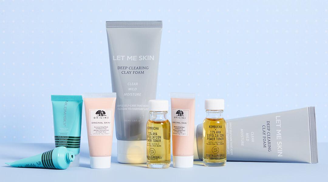 Skincare products from various brands on light blue background Desktop