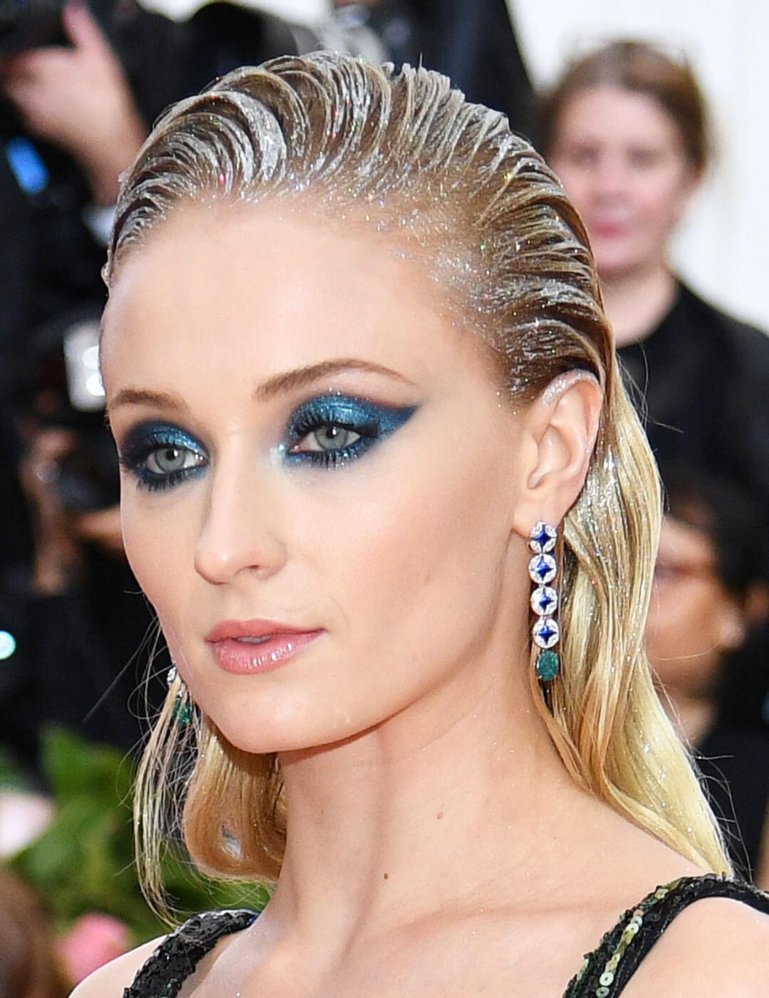 Sophie Turner looking glam in a metallic blue eyeshadow makeup look and silver hair accents on the 2019 Met Gala red carpet Mobile