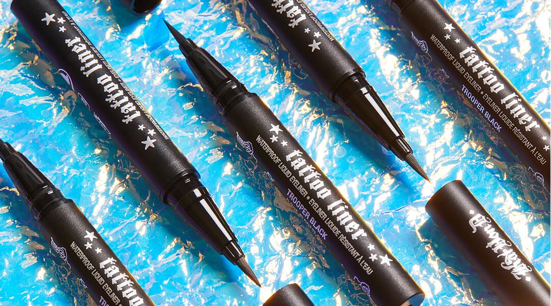 Flat lay image of KVD VEGAN BEAUTY Tattoo Liners agains a blue background Desktop