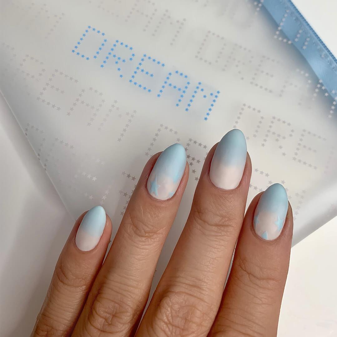 Close-up of woman's nails with white to blue ombre nail art mani on top of the IPSY January 2021 Glam Bag Desktop